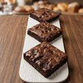 Three fudge brownies on a white serving board